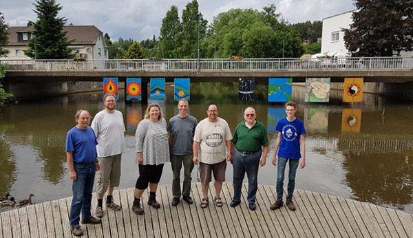 Bilder unter Brücke, vorn einige Künstler und ihre Helfer beim Aufhängen